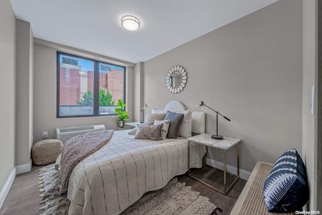 bedroom with wood-type flooring and a wall mounted AC