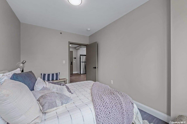 bedroom with hardwood / wood-style flooring and stainless steel refrigerator