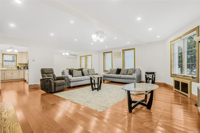 living room with light hardwood / wood-style floors, a wall unit AC, and a chandelier