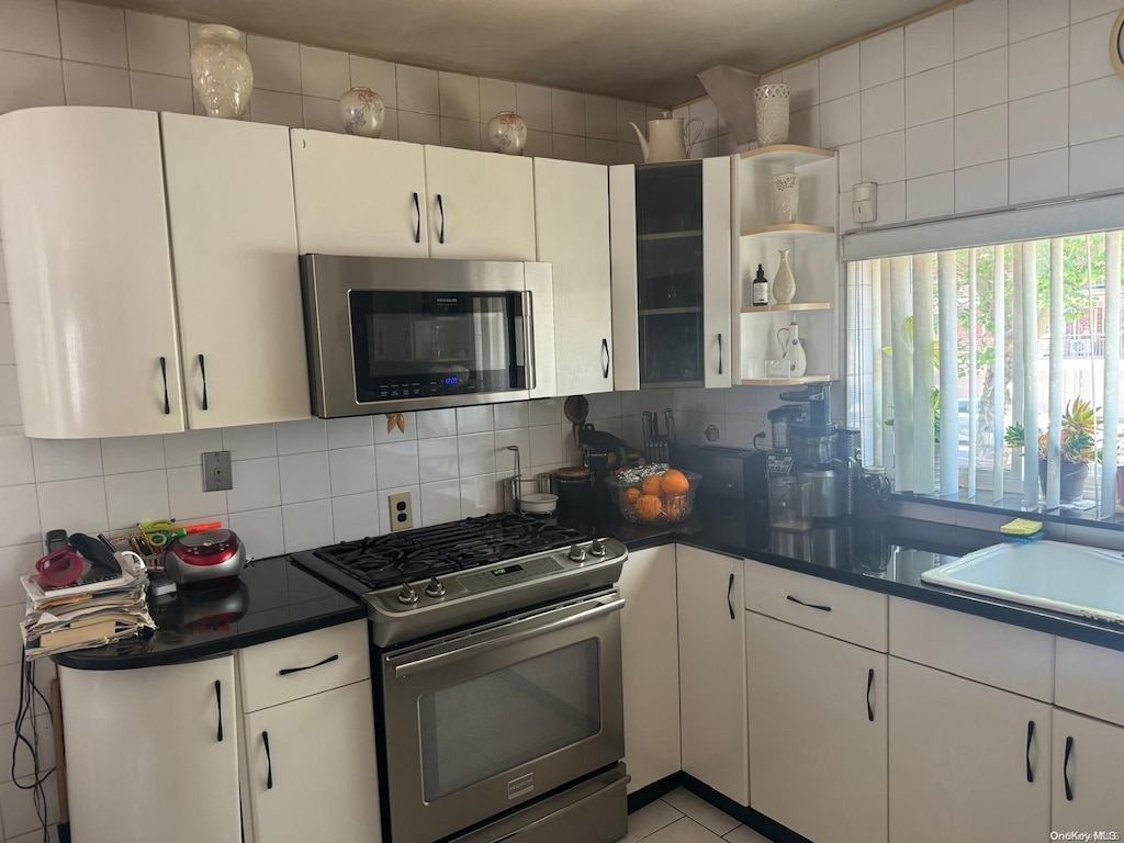 kitchen featuring appliances with stainless steel finishes, tasteful backsplash, white cabinetry, and sink