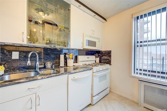 kitchen with backsplash, radiator, dark stone counters, white appliances, and white cabinetry