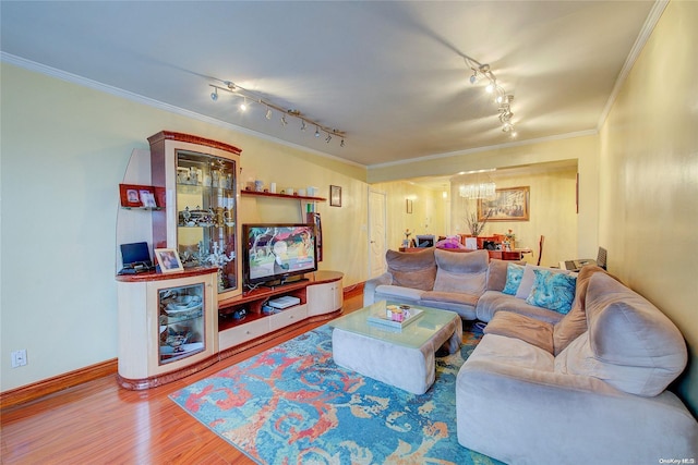 living room featuring rail lighting, ornamental molding, a notable chandelier, and hardwood / wood-style flooring