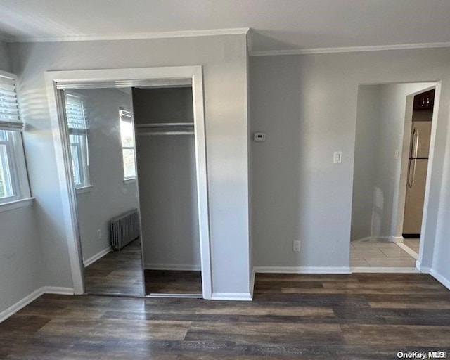 unfurnished bedroom with stainless steel fridge, dark hardwood / wood-style flooring, a closet, and radiator heating unit