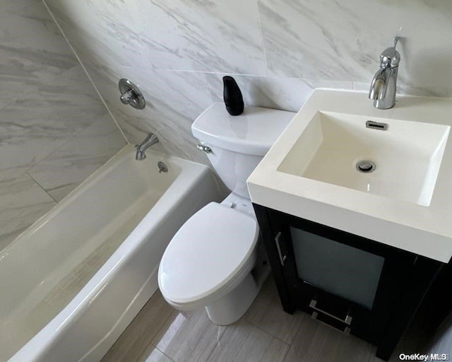 bathroom featuring a washtub, vanity, tile walls, and toilet