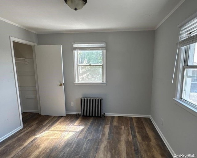 unfurnished bedroom with radiator heating unit, dark hardwood / wood-style flooring, a closet, and multiple windows