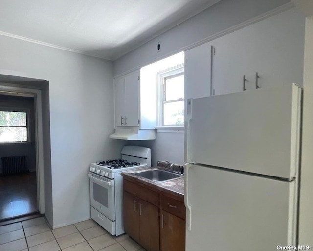 kitchen with white cabinetry, radiator heating unit, sink, white appliances, and light tile patterned flooring