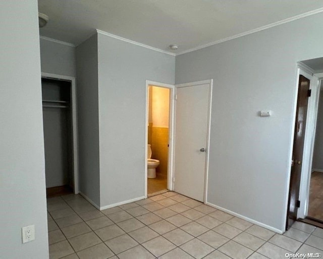 unfurnished bedroom featuring crown molding, a closet, and light tile patterned floors