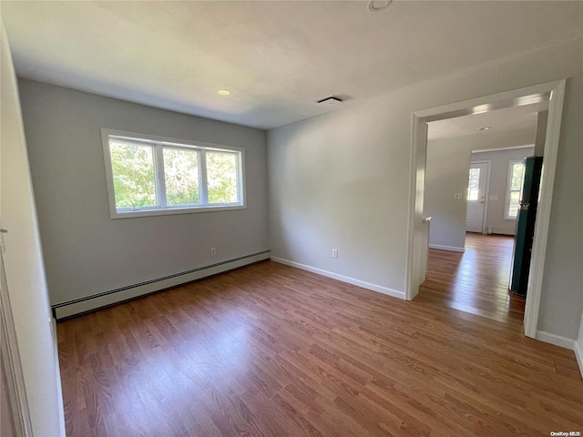 unfurnished room with hardwood / wood-style flooring and a baseboard heating unit