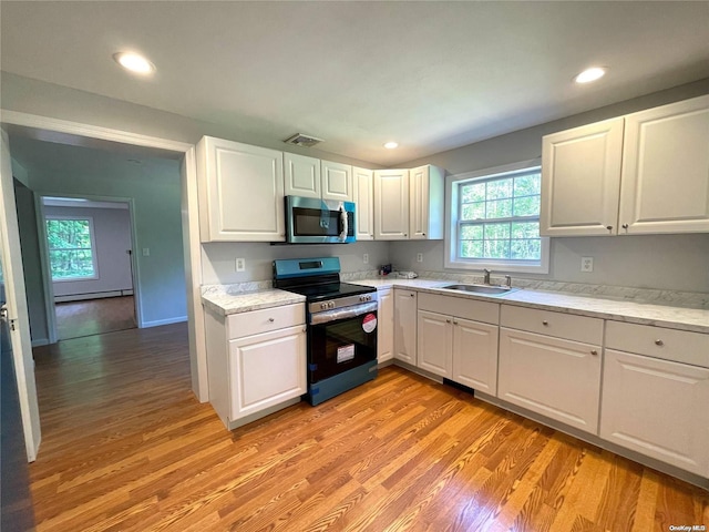 kitchen with white cabinetry, sink, light wood-type flooring, and appliances with stainless steel finishes