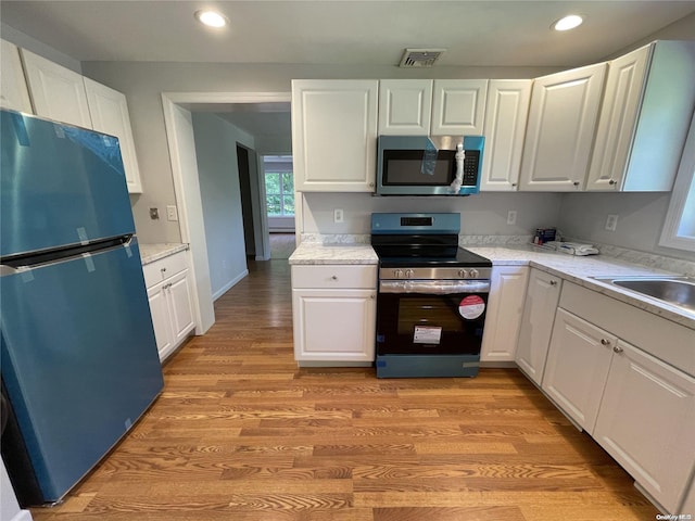 kitchen featuring light wood-type flooring, white cabinetry, and stainless steel appliances