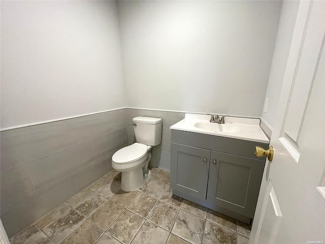 bathroom featuring vanity, toilet, and tile walls