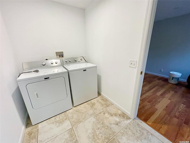 laundry area featuring washing machine and dryer and light hardwood / wood-style flooring