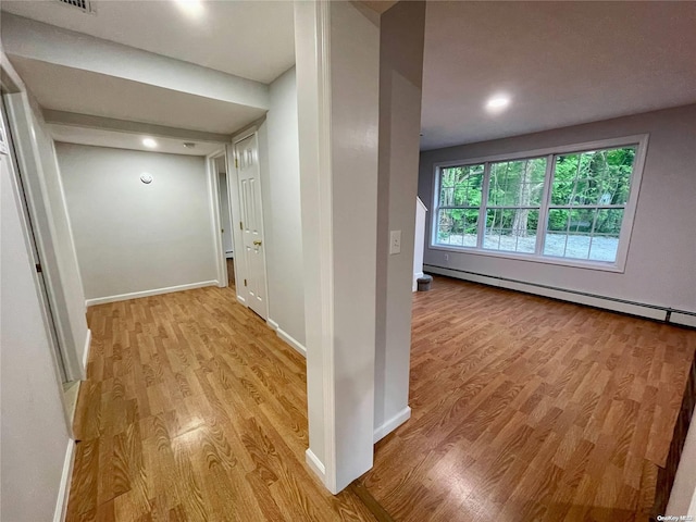 hall with light hardwood / wood-style flooring and a baseboard heating unit