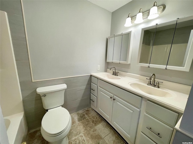 bathroom featuring vanity, tile walls, and toilet