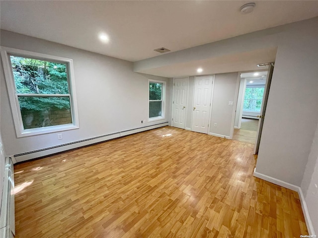 interior space featuring light hardwood / wood-style floors, baseboard heating, and multiple windows