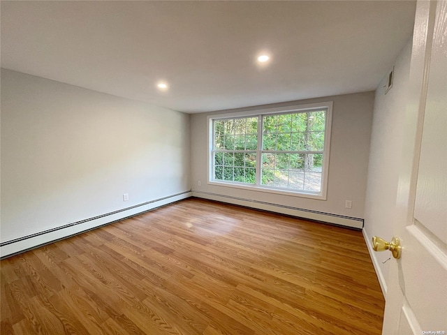 unfurnished room with a baseboard heating unit and light wood-type flooring