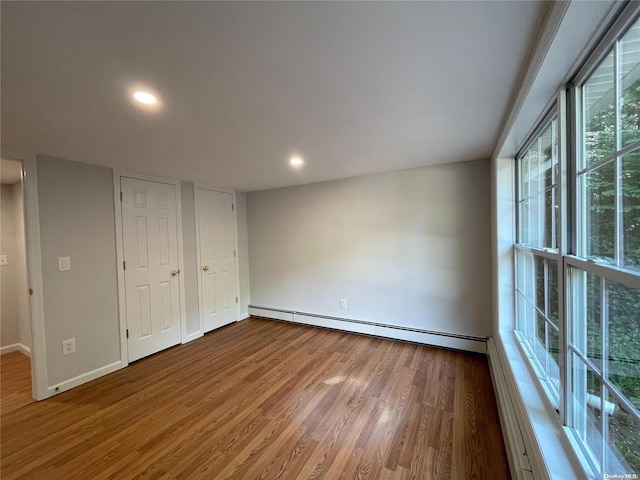 unfurnished room featuring baseboard heating and hardwood / wood-style floors