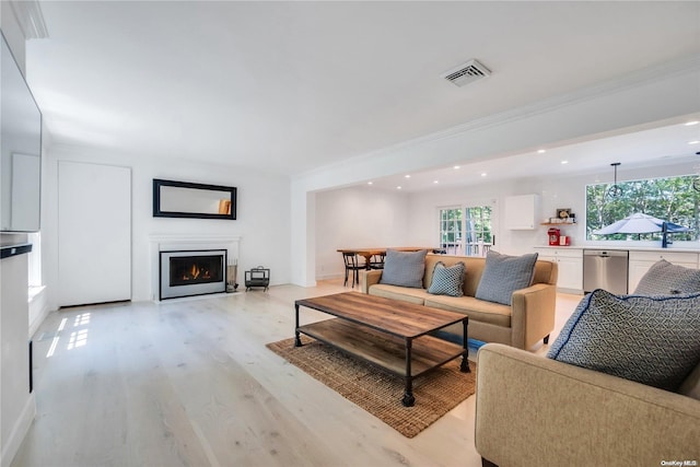 living room featuring light hardwood / wood-style flooring, ornamental molding, and sink