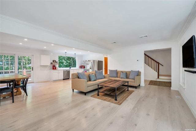 living room with light wood-type flooring, crown molding, and sink