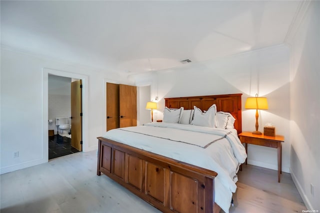 bedroom with light hardwood / wood-style floors, ornamental molding, and connected bathroom