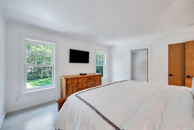 bedroom with concrete flooring, ornamental molding, and multiple windows