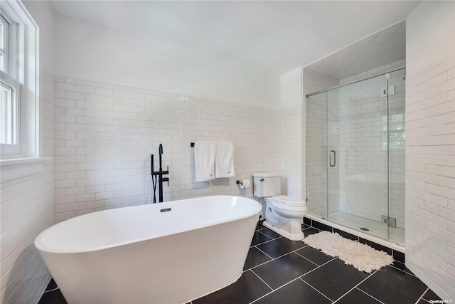 bathroom featuring tile patterned flooring, plus walk in shower, tile walls, and toilet