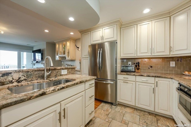 kitchen with dark stone counters, backsplash, sink, and stainless steel appliances