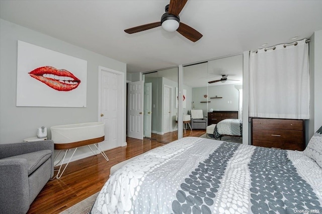 bedroom featuring dark hardwood / wood-style floors, ceiling fan, and multiple closets