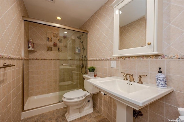 bathroom featuring tile patterned flooring, a shower with shower door, tile walls, and toilet