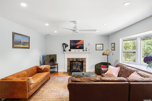 living room with a wood stove, ceiling fan, and light hardwood / wood-style floors