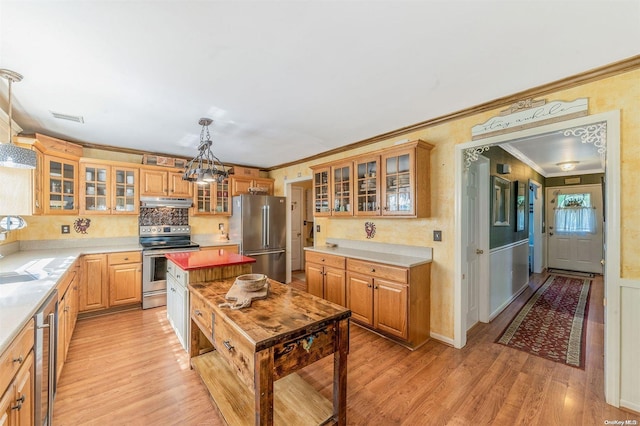 kitchen featuring light wood-type flooring, stainless steel appliances, crown molding, a chandelier, and hanging light fixtures