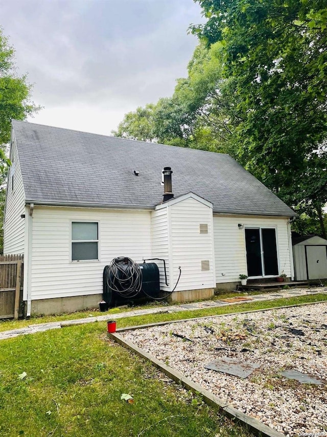 back of house featuring a storage unit and a lawn