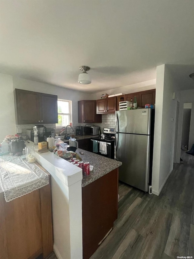 kitchen with tasteful backsplash, kitchen peninsula, dark wood-type flooring, and appliances with stainless steel finishes