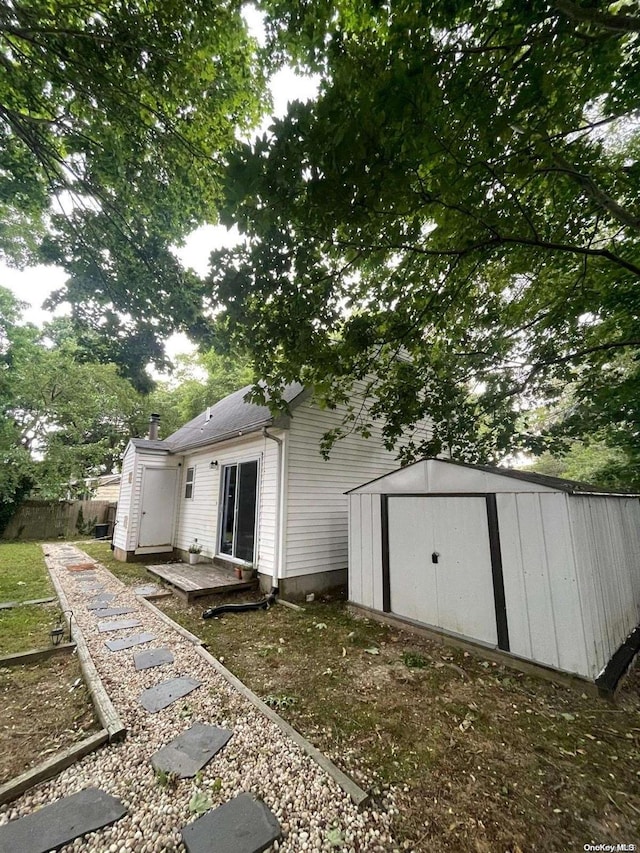 back of house with a storage unit