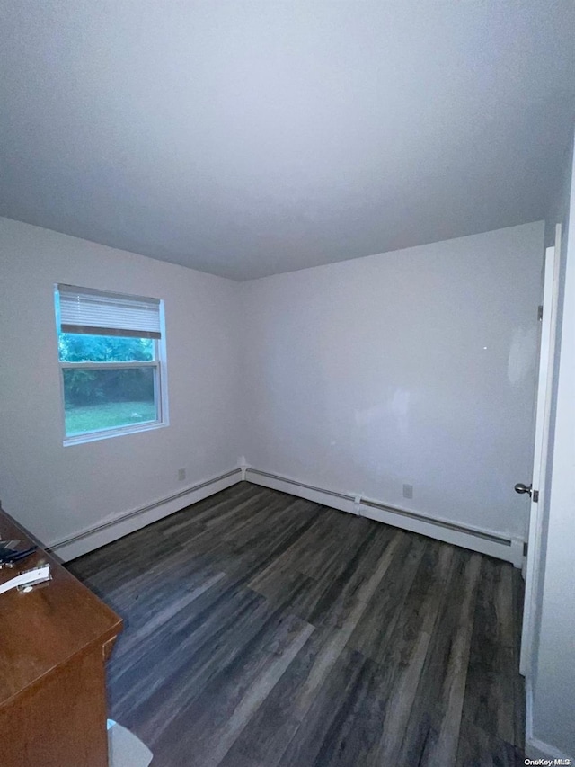 unfurnished room with baseboard heating and dark wood-type flooring