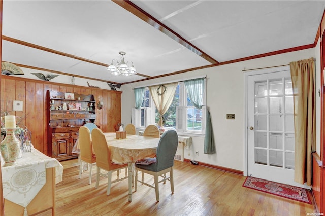 dining space featuring wood walls, crown molding, a chandelier, and light wood-type flooring