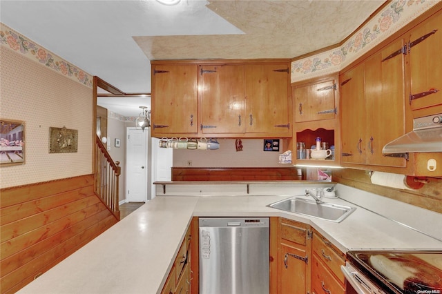 kitchen featuring stainless steel dishwasher, wood walls, and sink