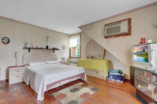 bedroom featuring hardwood / wood-style floors, ornamental molding, radiator, and a wall mounted AC