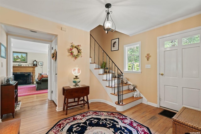 foyer entrance with crown molding and light hardwood / wood-style floors