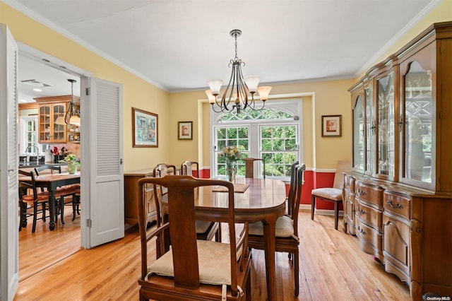 dining area featuring crown molding, sink, a chandelier, and light wood-type flooring