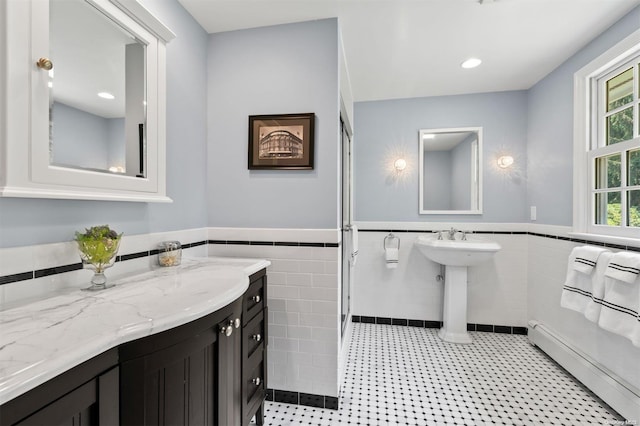 bathroom featuring sink, tile walls, and a baseboard heating unit