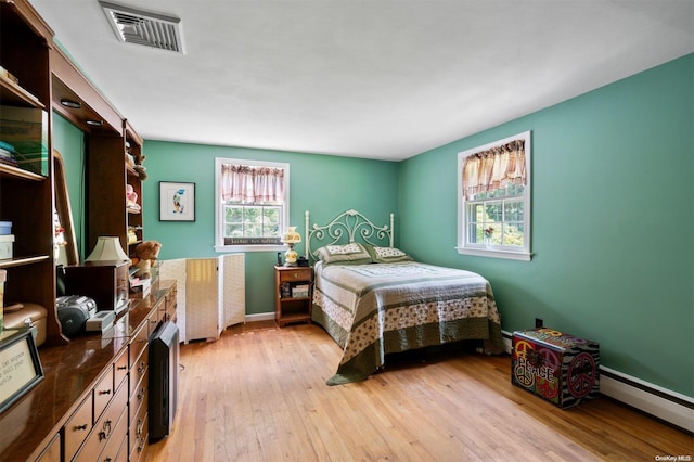 bedroom featuring light hardwood / wood-style floors and a baseboard heating unit