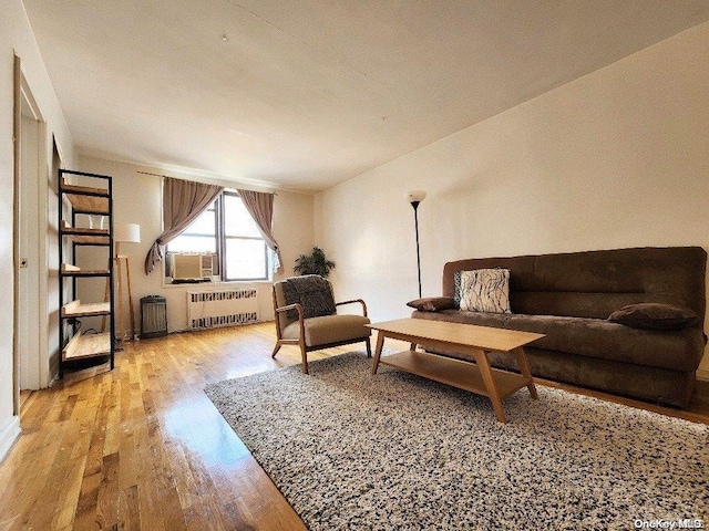 living room with cooling unit, light wood-type flooring, and radiator heating unit