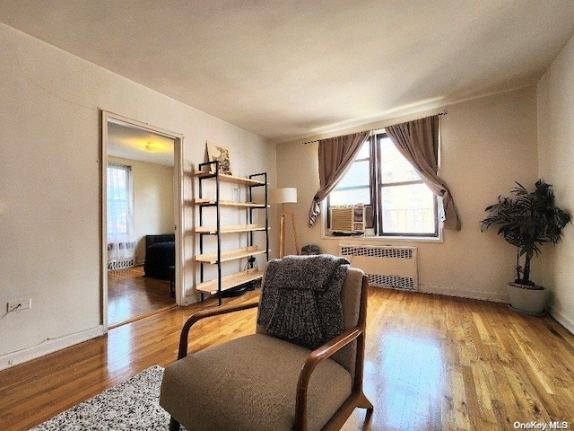 sitting room with radiator heating unit, cooling unit, and hardwood / wood-style floors