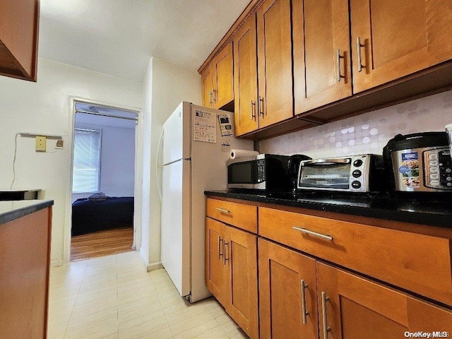 kitchen featuring white refrigerator and backsplash