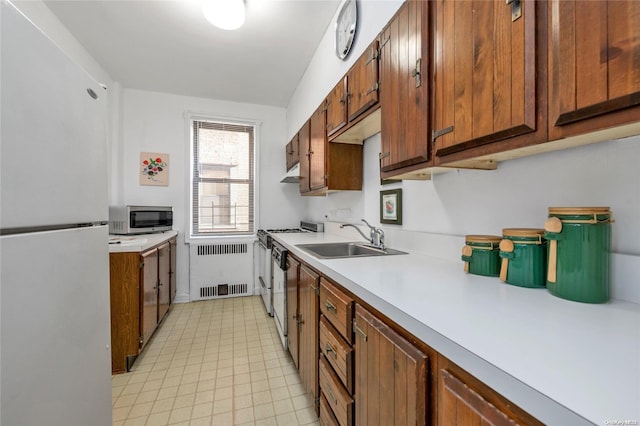 kitchen featuring freestanding refrigerator, a sink, light countertops, under cabinet range hood, and stainless steel microwave