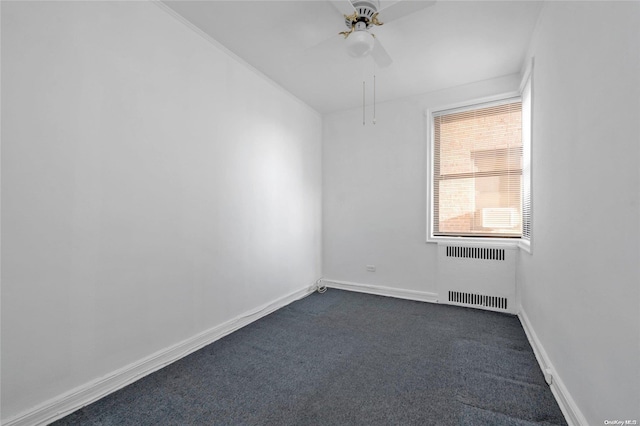 spare room with radiator, baseboards, a ceiling fan, and dark colored carpet