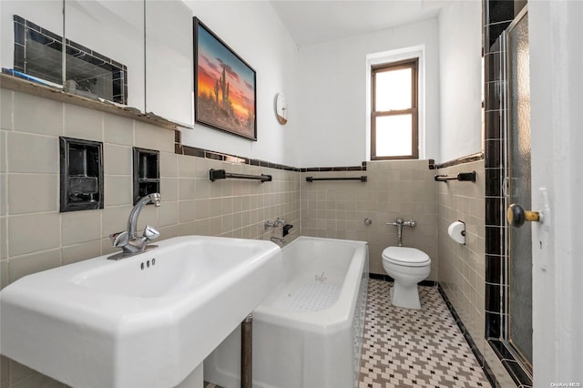 bathroom featuring a sink, a shower, wainscoting, tile walls, and toilet