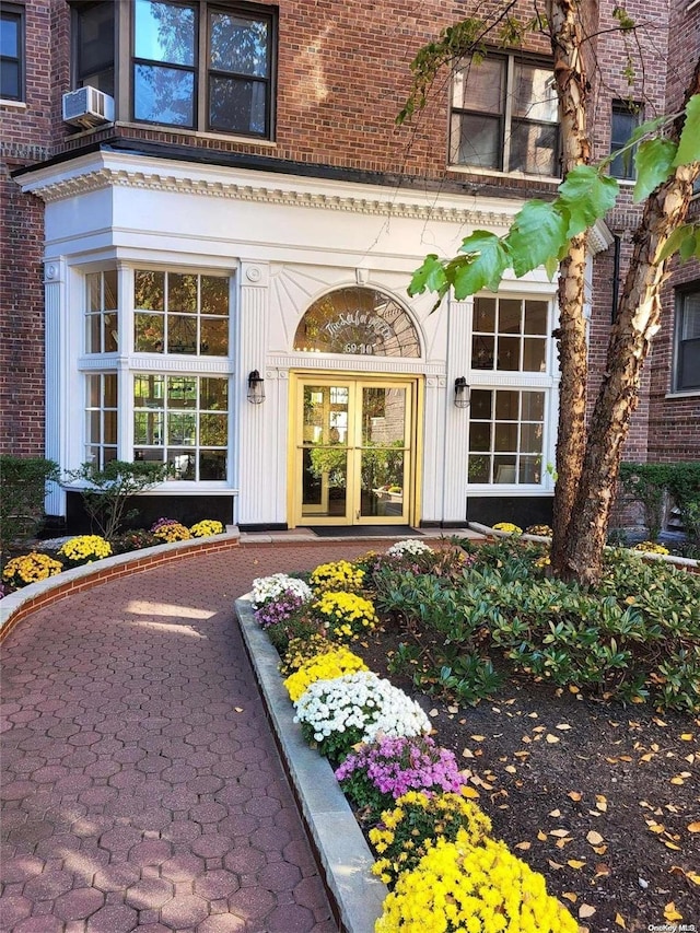 view of exterior entry featuring cooling unit, french doors, and brick siding