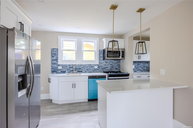 kitchen with decorative backsplash, stainless steel appliances, sink, white cabinetry, and hanging light fixtures